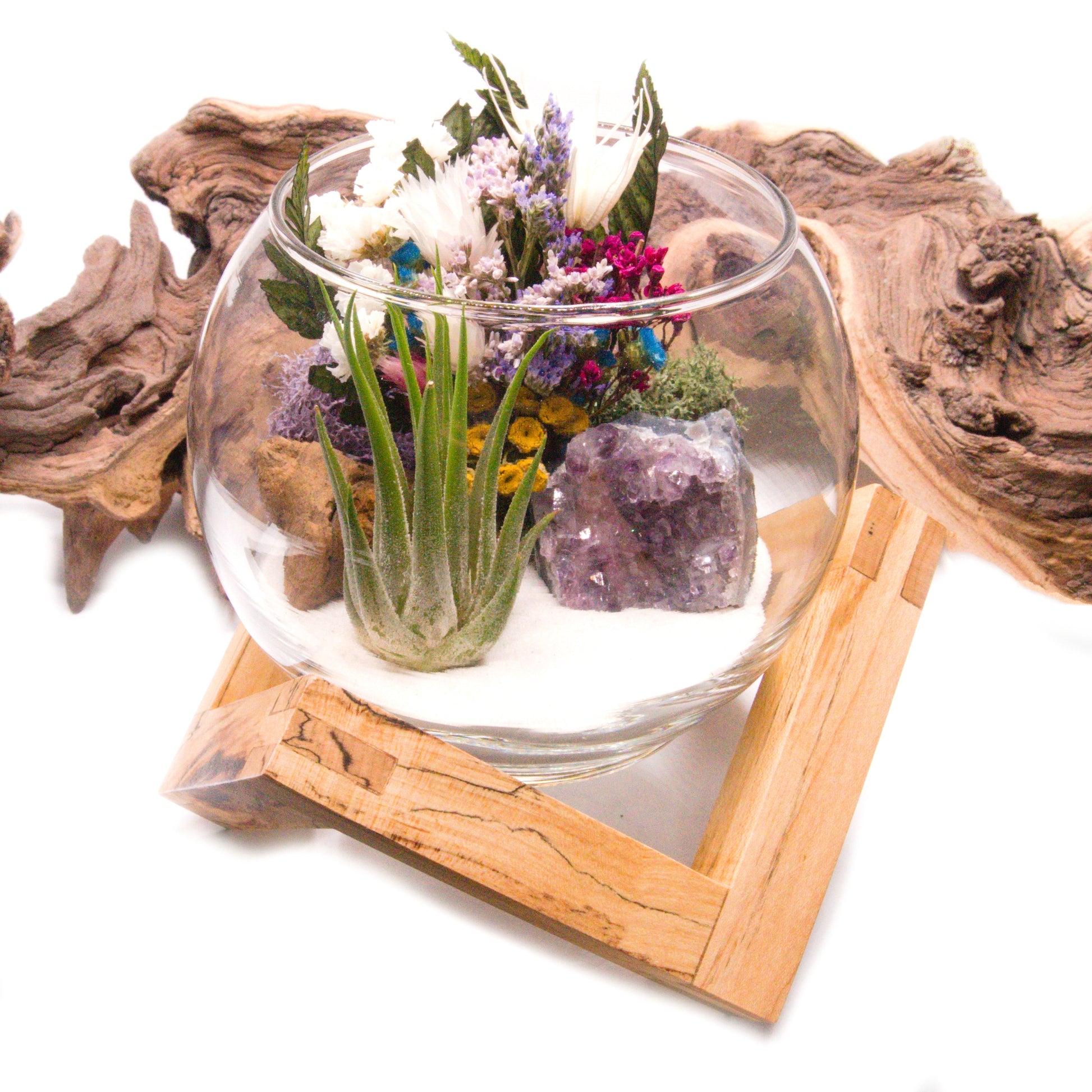 Airplant terrarium in a glass bowl with a bouquet of dried flowers, moss, wood and a raw amethyst crystal.